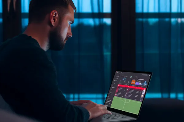 678DB Mobile App — Your complete hub for casino and sports A man focused on his laptop with live stats in the background, highlighting the dedicated sports and gaming features of the 678DB mobile app.