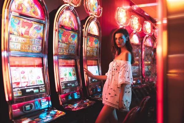 678DB Slots — Thousands of exciting themes and jackpots A stylish woman beside vibrant slot machines displaying glowing sevens, showcasing the variety of top slots at 678DB.